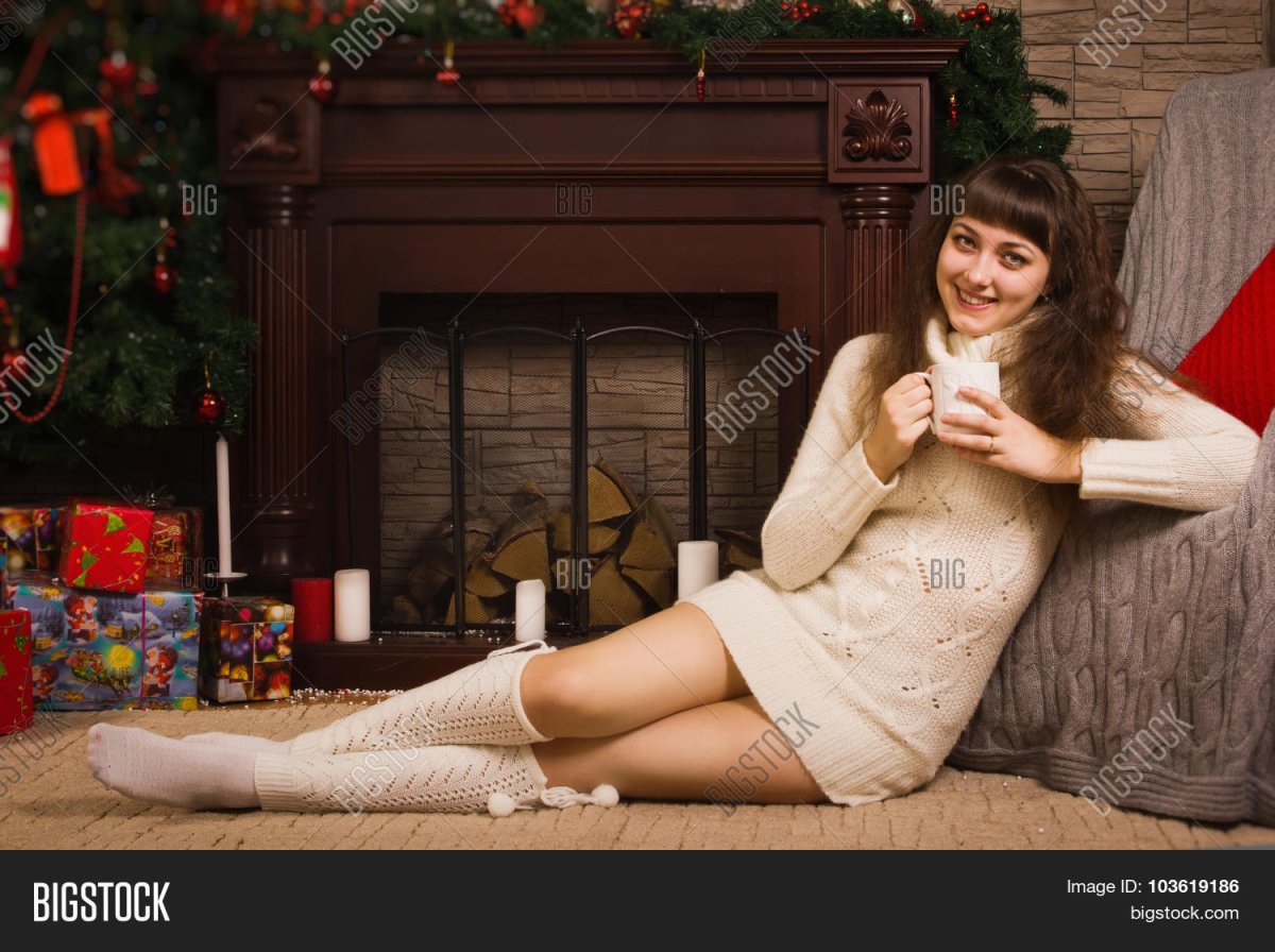Девушка в свитере у камина