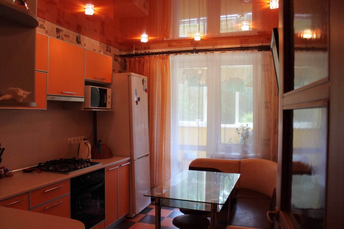 Холодильник у окна с балконом на кухне