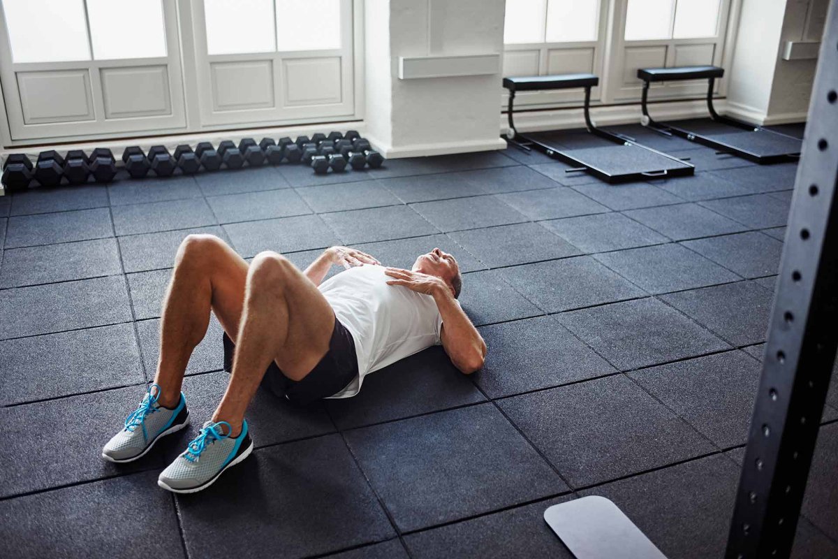 Человек лежит на полу спортзала