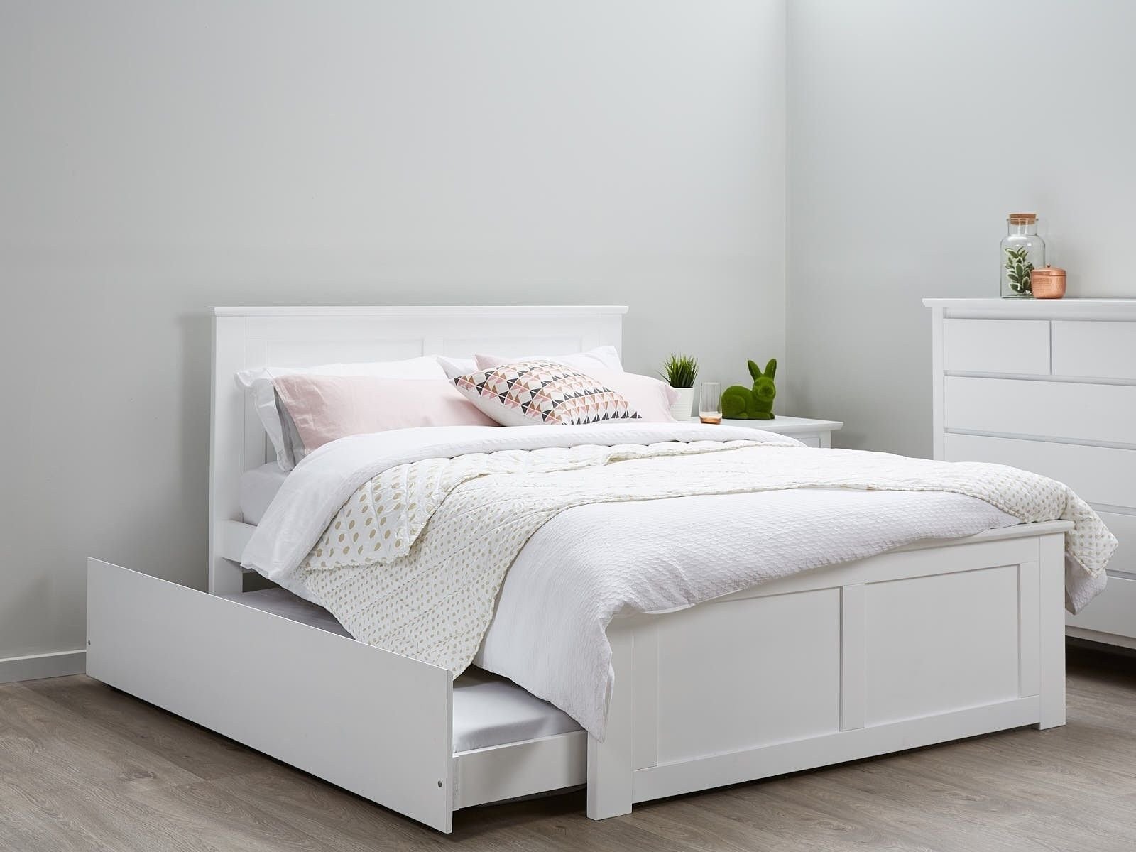белая кровать с деревянным изголовьем