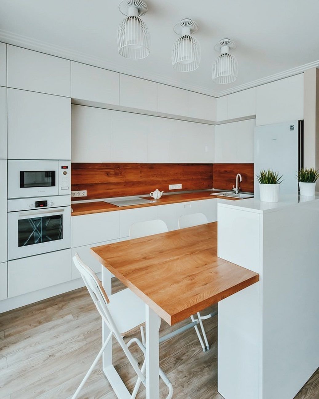 Белая глянцевая кухня с деревянной столешницей и фартуком