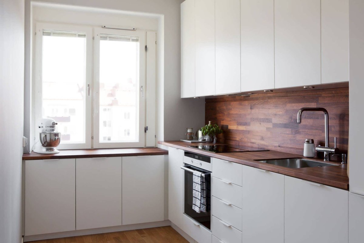 Белая кухня с деревянной столешницей и фартуком