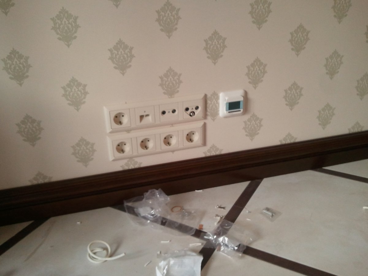 Розетка и выключатель на белой стене