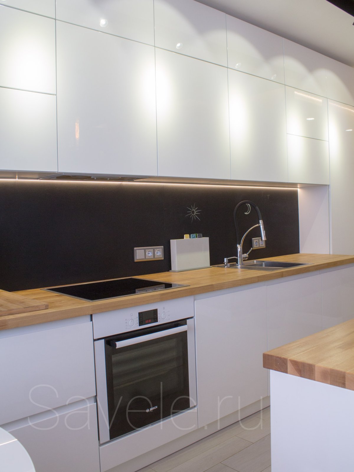 Белая кухня с черным фартуком и деревянной столешницей